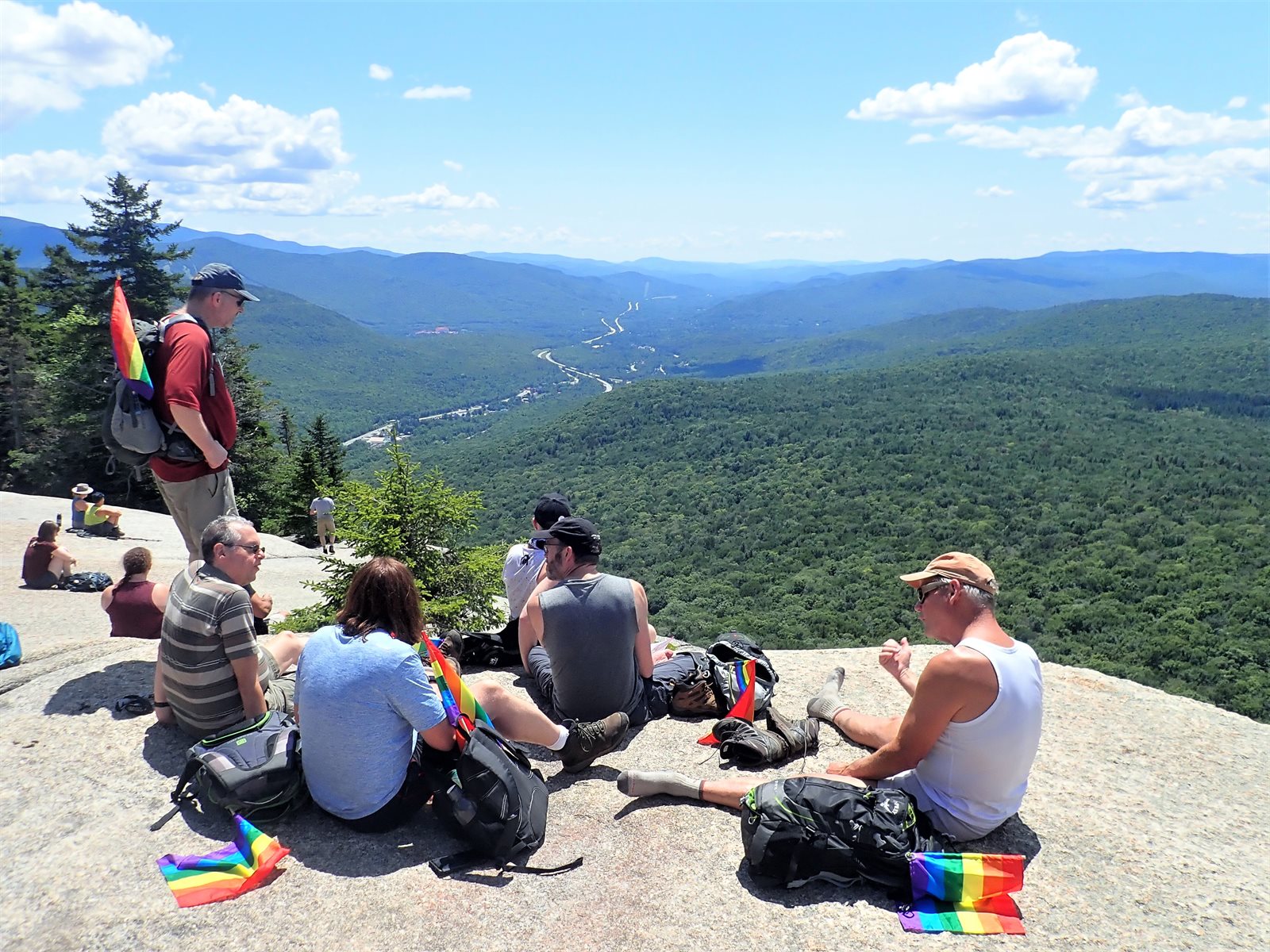 GayOutdoors members resting for lunch on a sunny summit ledge overlooking the mountains