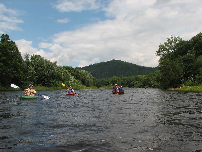 GayOutdoors members paddling kayaks and a canoe on a calm river